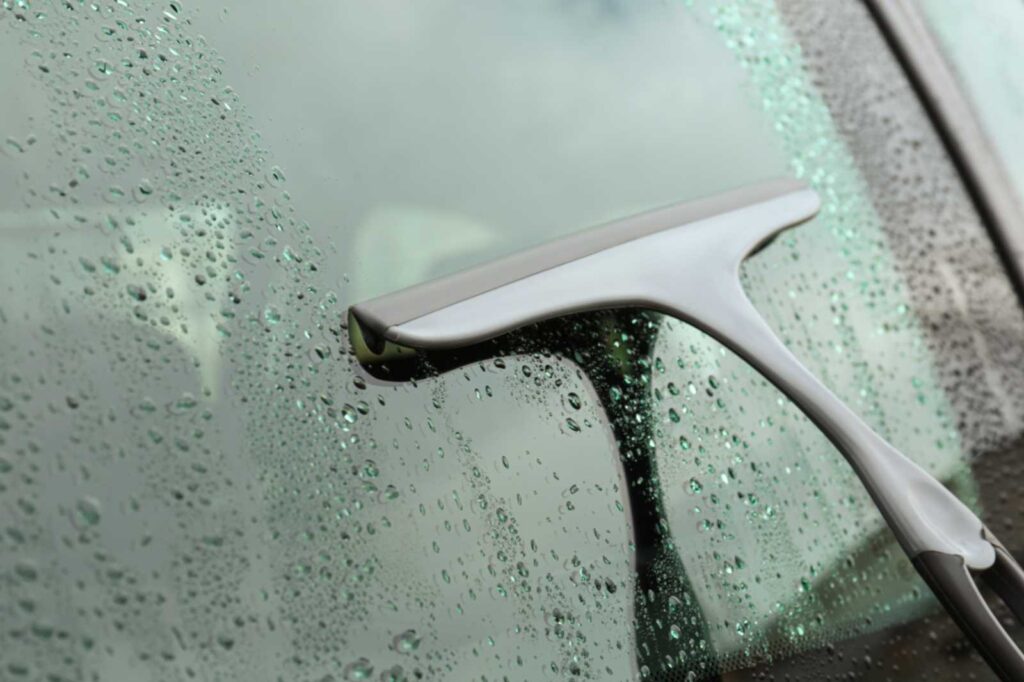 Person cleaning a tinted window with a squeegee