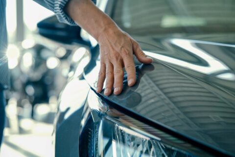 A person’s hand resting on the hood of a shiny car in Portland, OR