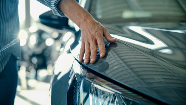A person’s hand resting on the hood of a shiny car in Portland, OR